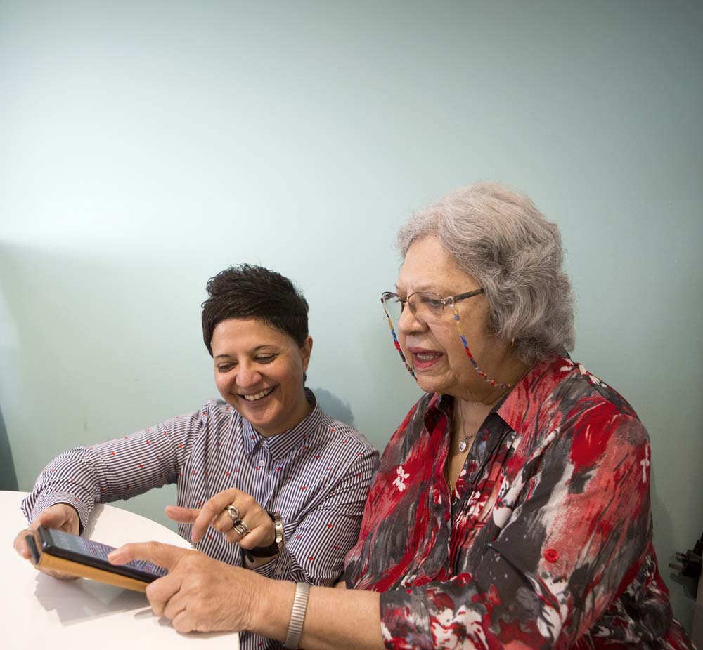Carer instructing women with mobile device.